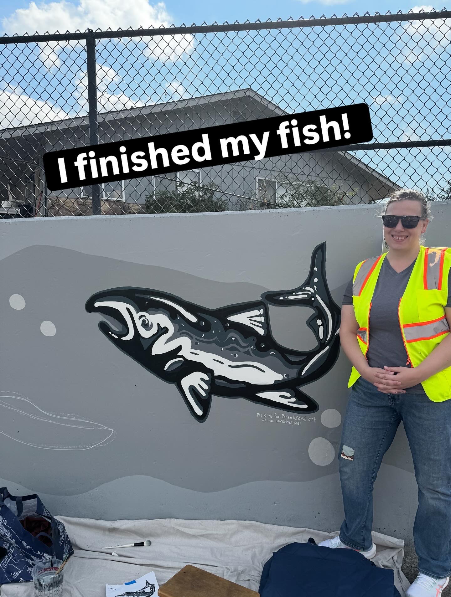 Jenna stands near her painting of a salmon, bold black, grey and white lines